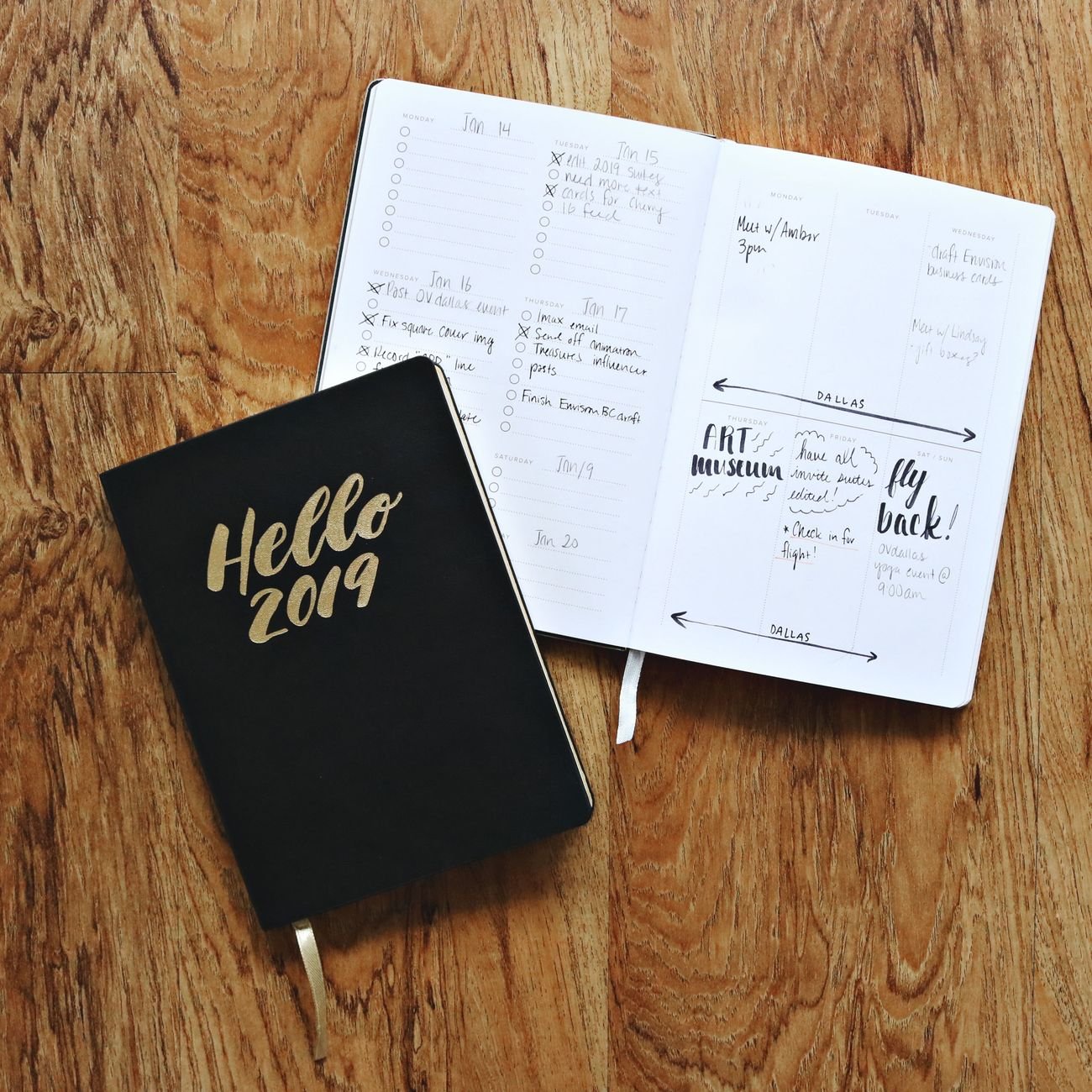 Two open journals on a wooden floor showcasing planning and organization.