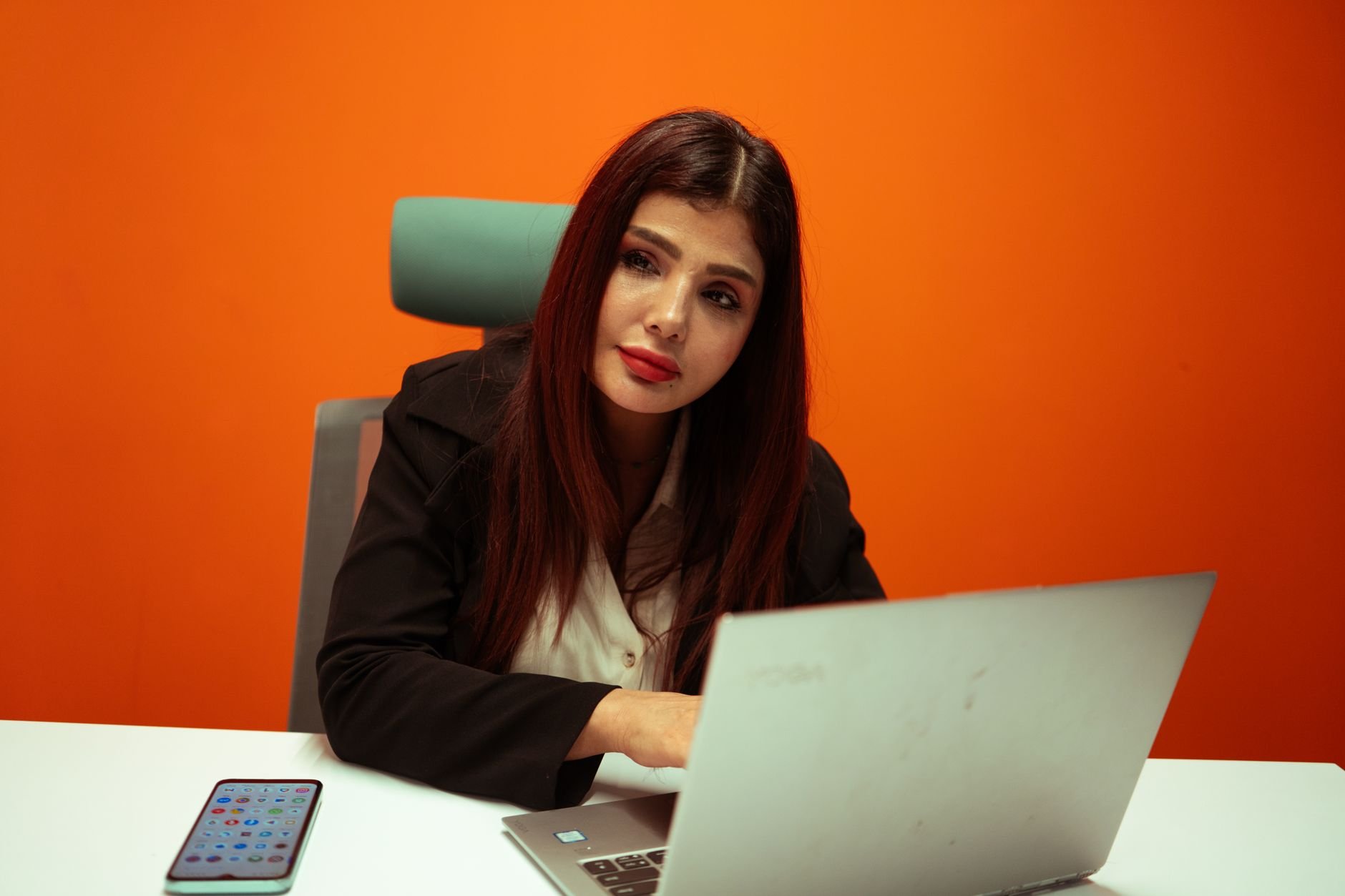 Focused businesswoman working on a laptop at a modern office desk.