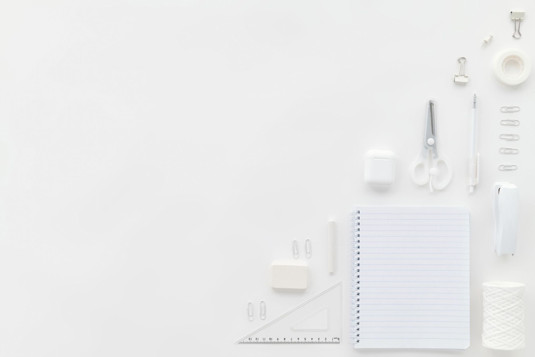 Flat lay of white stationery items on a minimalist office desk with ample copy space.